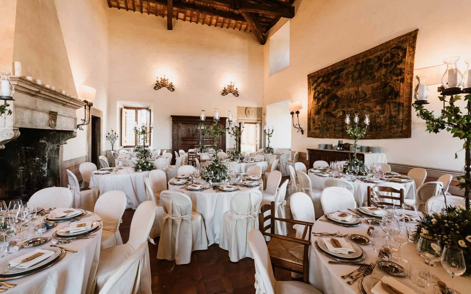 sala del castello farnese a roma allestita per cerimonia con tavoli apparecchiati in bianco con fiori, segnaposto